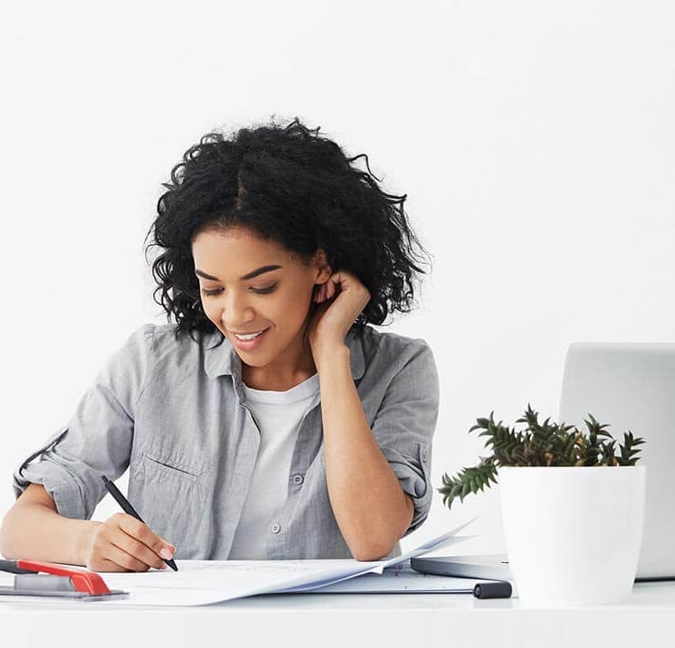 Event planner smiling while writing plans at her desk